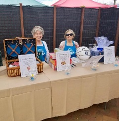 Two women stand behind items up for auction