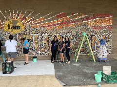 The Hughes team poses in front of mural