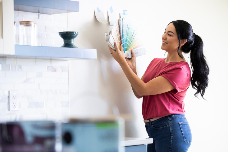 A woman holds a color pallet against her wall.