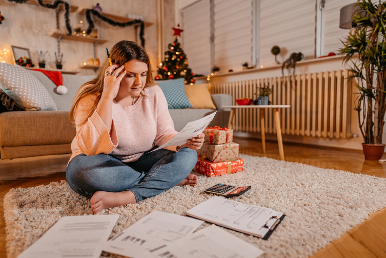 A worried woman sits on her floor with receipts in front of her.