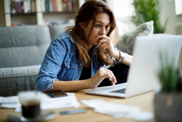 A young woman looks worried as she works on her laptop