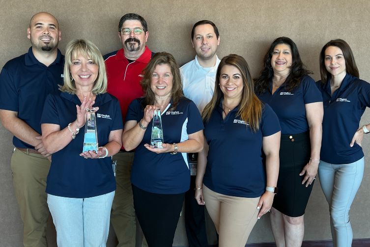 The Hughes marketing team poses for a photo holding two Diamond awards.