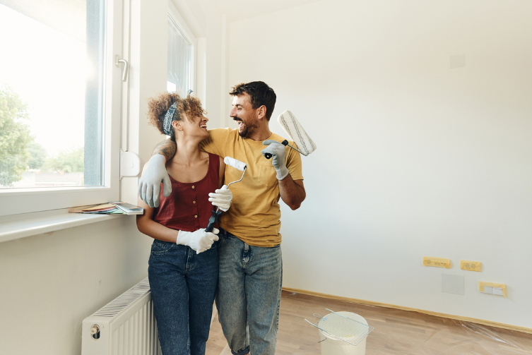A couple laugh and smile as the hold paint brushes