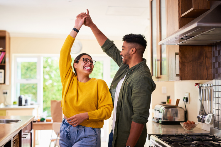 A young couple dancing in the kitchen together.