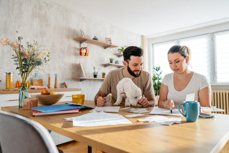 A young couple and their small white dog look over at finances