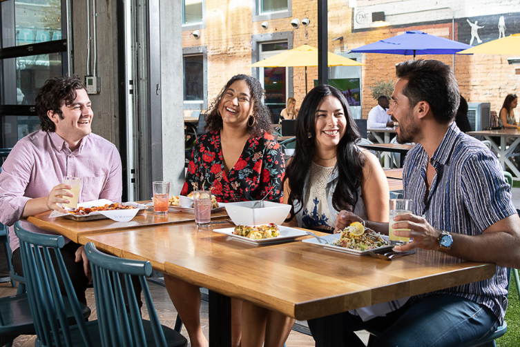 A group of diverse friends sitting at a table enjoying brunch at Tucson's The Monica.