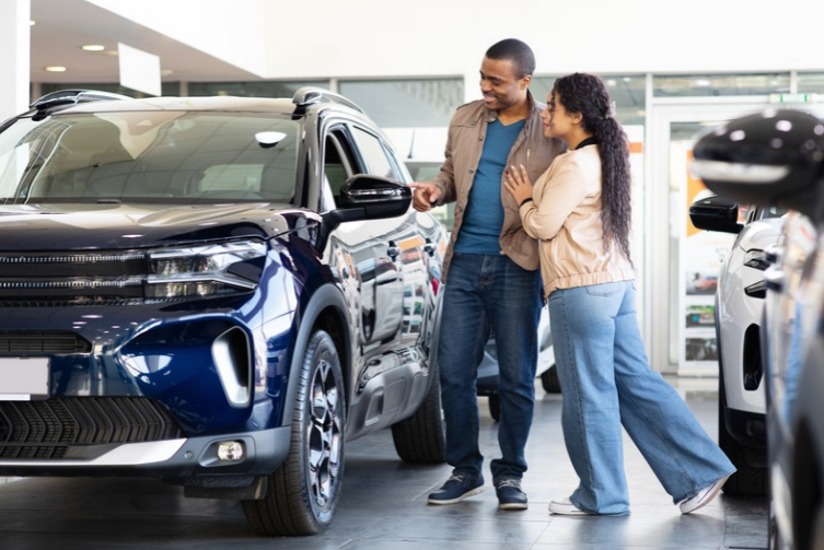 A couple looks at a SUV at a car dealership
