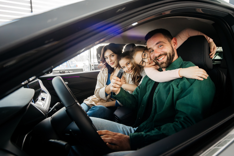 A family poses inside a car, holding key to new car