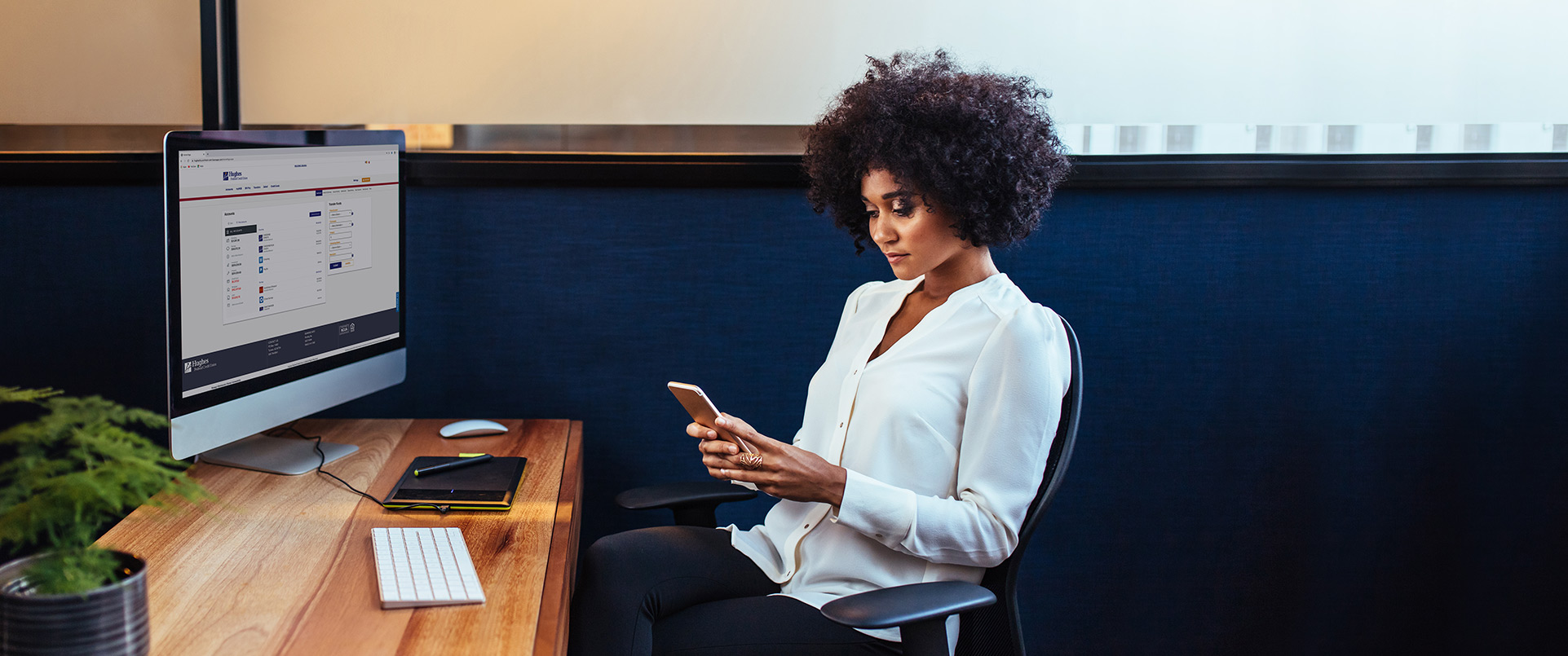 Woman sitting at desk with a cell phone