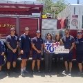 Fire fighters and Hughes team in front of fire truck.